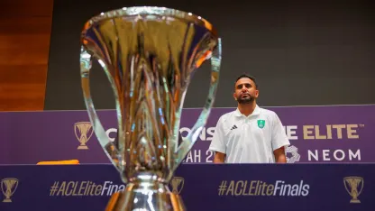 Al Ahli's Riyad Mahrez poses alongside the AFC Champions League Elite trophy