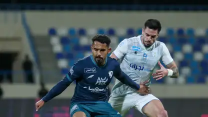 Al Okhdood and Al Tai players battle for the ball